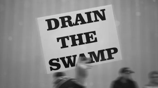 A man holds a Drain The Swamp sign up