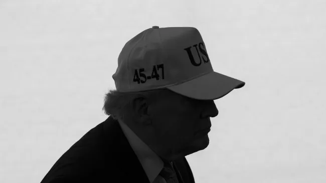 Trump stands in a shadow by a wall