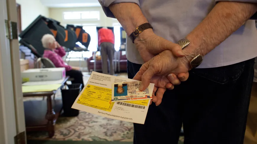 A voter holds his ballot and his ID