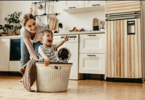 woman playing with child while laundry machine does the wash